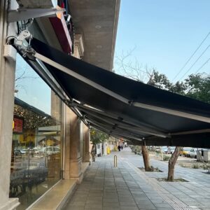 سایبان اتوماتیک بازویی نصب شده کنار فضای نشیمن ویلا